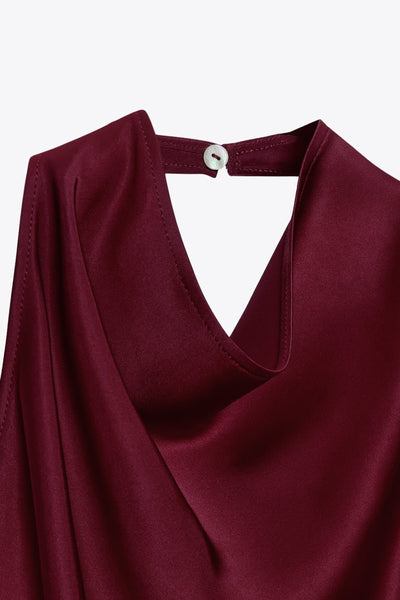 Blusa larga satinada, de fit fluido, sin mangas, cuello halter fluido, escote en espalda, bajo asimétrico y cierre posterior con botón y ojal.