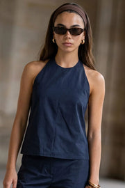 Blusa de fit fluido, cuello halter con nudo amarrable posterior, escote en espalda y cierre posterior con trabilla ajustable.