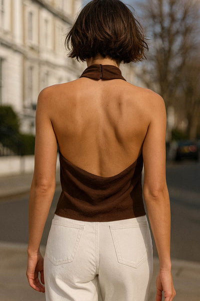 Blusa halter de cuello alto fluido, sin mangas, fit recto, escote en espalda y bajo asimétrico frontal. Cierre posterior con broche oculto.