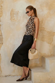 Blusa corta de fit fluido, sin mangas, estampado animal, cuello halter fluido con plisados, escote en espalda y lazo amarrable posterior. Cierre posterior con botón y ojal.