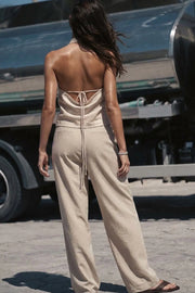 Blusa corta de fit fluido, sin mangas, cuello halter fluido con plisados, escote en espalda y lazo amarrable posterior. Cierre posterior con botón y ojal.