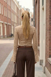 Blusa de encaje, fit ajustado, cuello barco, manga larga con puño amplio y detalle decorativo en bordes.