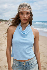Blusa de cuello halter fluido, escote en espalda con lazo amarrable posterior, cierre con botón y ojal.