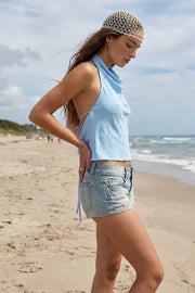 Blusa de cuello halter fluido, escote en espalda con lazo amarrable posterior, cierre con botón y ojal.