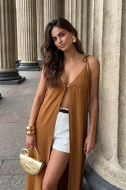 Blusa larga de fit fluido, tirantes delgados con nudo ajustable, escote v con cortes, abertura frontal y cierre con botón.