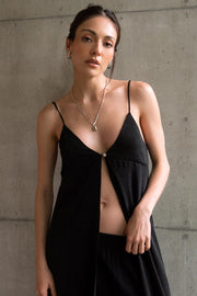 Blusa larga de fit fluido, tirantes delgados con nudo ajustable, escote v con cortes, abertura frontal y cierre con botón.