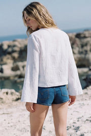 Blusa corta de fit fluido, manga larga con puño amplio, escote v con solapa y cierre frontal con lazos amarrables.