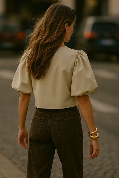 Blusa corta de fit recto, cuello redondo, manga corta amplia globo con volumen en borde, cierre frontal con broches ocultos y bajo curveado frontal.