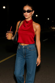 Blusa corta satinada de cuello halter con escote fluido, sin mangas y escote en espalda con tirantes delgados ajustables.