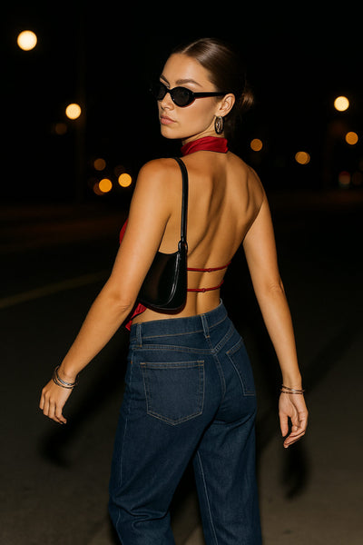 Blusa corta satinada de cuello halter con escote fluido, sin mangas y escote en espalda con tirantes delgados ajustables.