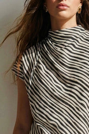 Blusa de estampado rayas, cuello alto fluido, plisados en hombros, manga corta seguida y fit recto. Cierre posterior con botón y ojal.