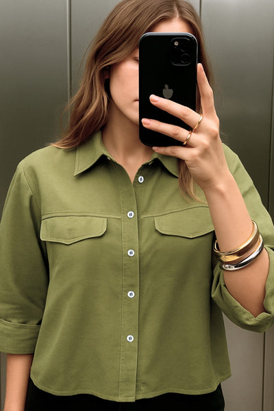 Camisa corta de fit oversized, manga 3/4 amplia con doblez en puños, cuello camisero, bolsillos frontales decorativos con cartera y pinza de amplitud en espalda. Cierre frontal con hilera de botones.