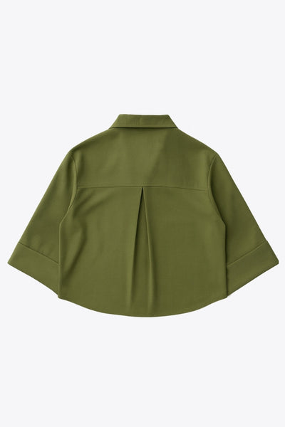 Camisa corta de fit oversized, manga 3/4 amplia con doblez en puños, cuello camisero, bolsillos frontales decorativos con cartera y pinza de amplitud en espalda. Cierre frontal con hilera de botones.