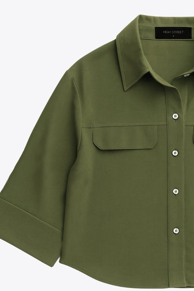 Camisa corta de fit oversized, manga 3/4 amplia con doblez en puños, cuello camisero, bolsillos frontales decorativos con cartera y pinza de amplitud en espalda. Cierre frontal con hilera de botones.