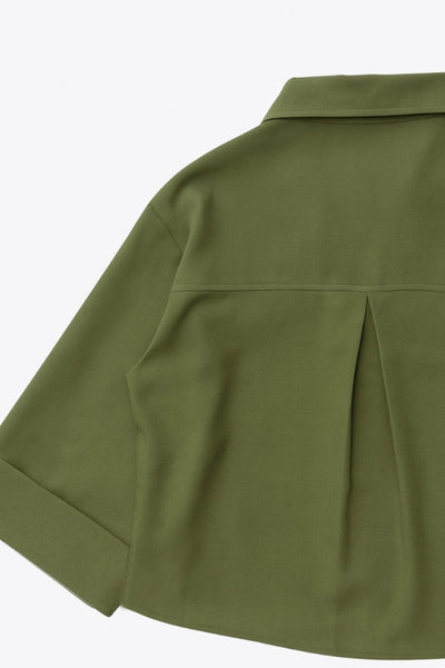 Camisa corta de fit oversized, manga 3/4 amplia con doblez en puños, cuello camisero, bolsillos frontales decorativos con cartera y pinza de amplitud en espalda. Cierre frontal con hilera de botones.