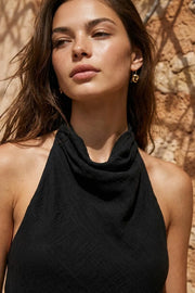 Blusa asimétrica de fit fluido, sin mangas, cuello halter fluido con plisados, escote en espalda y lazo amarrable posterior. Cierre posterior con botón y ojal. Detalle de bajo frontal asimétrico.