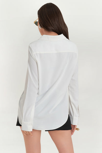 Blusa de fit oversized, manga larga con puño abotonado, cuello sport y bajo curveado.