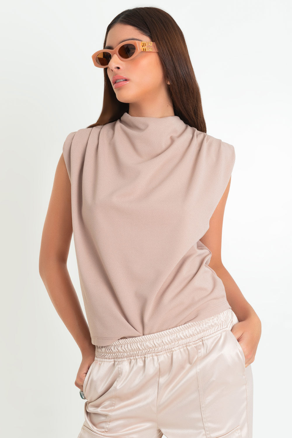 Blusa de fit oversized, sin mangas y cuello alto con detalles plisados en hombros.