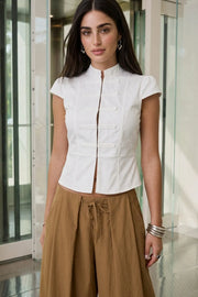Blusa corta de fit ajustado, manga corta con plisados, cuello mao, peplum con olanes en bajo, cierre frontal con broches ocultos y detalles decorativos frontales.