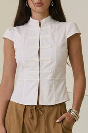 Blusa corta de fit ajustado, manga corta con plisados, cuello mao, peplum con olanes en bajo, cierre frontal con broches ocultos y detalles decorativos frontales.