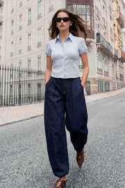 Camisa corta de estampado rayas, fit recto, manga corta abullonada con rib elástico en bordes, cuello camisero, cortes y plisados frontales. Cierre frontal con hilera de botones.