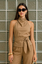Blusa corta de fit recto, halter con cuello fluido, sin mangas, lazo amarrable en cintura, cierre posterior con botón y ojal.