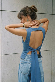 Blusa corta de fit ajustado, sin mangas, cuello redondo, pinzas frontales y cut out en espalda con lazo amarrable posterior. Cierre posterior con broche.