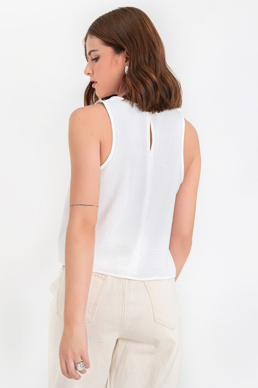 Blusa sin mangas de fit ligeramente oversized, cuello redondo y cierre posterior con botón y ojal.