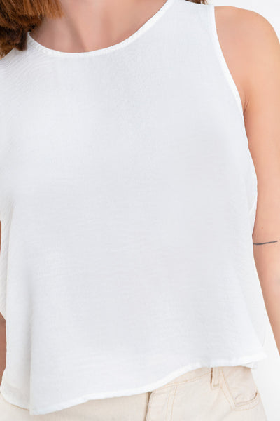 Blusa sin mangas de fit ligeramente oversized, cuello redondo y cierre posterior con botón y ojal.