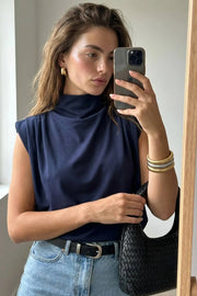 Blusa de fit oversized, sin mangas y cuello alto con detalles plisados en hombros.