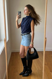 Blusa de fit oversized, sin mangas y cuello alto con detalles plisados en hombros.