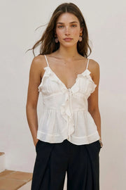 Blusa corta de tirantes delgados ajustables, escote v con olanes en borde, cortes frontales con plisados, peplum con olanes en bajo y cierre frontal con lazos amarrables.