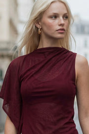 Blusa túnica asimétrica de una manga corta seguida con olanes, plisados en costados, bajo asimétrico y cuello barco. Cierre posterior con botón y ojal.