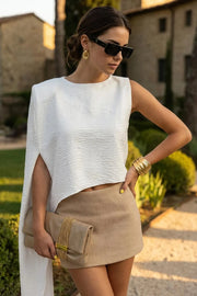 Blusa tipo túnica asimétrica, de cuello redondo, con hombreras, una manga corta seguida, fit fluido y bajo asimétrico.