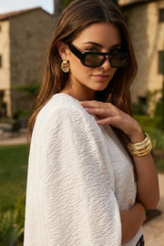 Blusa tipo túnica asimétrica, de cuello redondo, con hombreras, una manga corta seguida, fit fluido y bajo asimétrico.