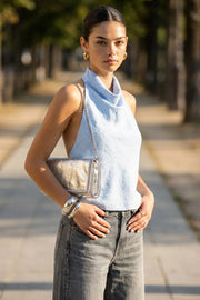 Blusa de cuello halter fluido, escote en espalda con lazo amarrable posterior, cierre con botón y ojal.