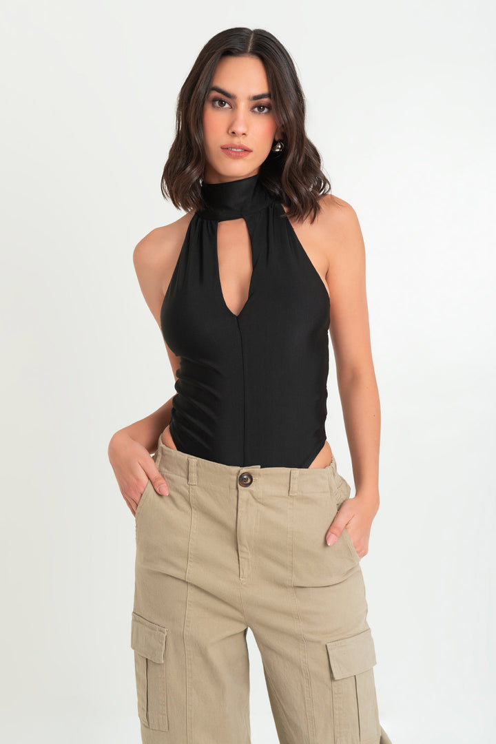 Woman wearing a black halter top and beige trousers against a white background.