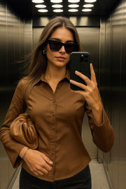 Camisa ajustada de cuello camisero, manga larga con amplitud y abertura en puños. Cierre frontal con hilera de botones.