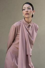 Camisa corta de fit fluido, manga larga amplia con puño abotonado, cuello camisero, detalle decorativo cruzado con plisados y olanes. Cierre frontal con hilera de botones en contraste. Detalle de pinza de amplitud en espalda.