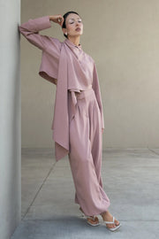 Camisa corta de fit fluido, manga larga amplia con puño abotonado, cuello camisero, detalle decorativo cruzado con plisados y olanes. Cierre frontal con hilera de botones en contraste. Detalle de pinza de amplitud en espalda.