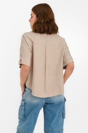 Camisa corta de fit recto, manga corta con doblez en borde y trabillas decorativas laterales, bolsillos frontales de parche, cuello camisero, bajo curveado y pinza de amplitud en espalda. Cierre frontal con hilera de botones en contraste