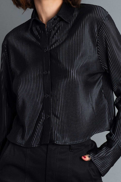 Camisa corta satinada de fit recto, manga larga con puño abotonado, cuello camisero y cierre frontal con hilera de botones en contraste. Detalle de plisado en textura de tejido.