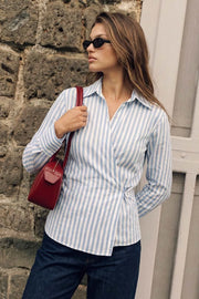 Camisa cruzada de estampado rayas, escote v, fit recto, manga larga con puño abotonado, cuello camisero, pinzas en espalda y cierre lateral con botón.
