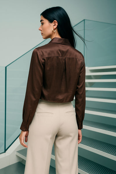 Camisa corta satinada de fit recto, cuello camisero, manga larga con puño abotonado, pinza de amplitud en espalda y cierre frontal con hilera de botones.