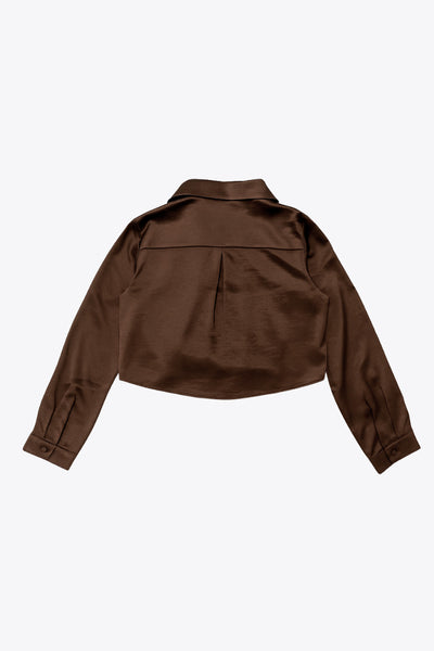 Camisa corta satinada de fit recto, cuello camisero, manga larga con puño abotonado, pinza de amplitud en espalda y cierre frontal con hilera de botones.