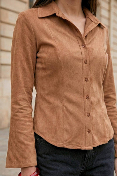 Camisa ajustada de gamuza, pinzas frontales, cuello camisero, bajo curveado, manga larga con amplitud y puño abotonado. Cierre frontal con hilera de botones.