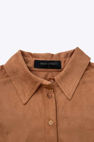 Camisa ajustada de gamuza, pinzas frontales, cuello camisero, bajo curveado, manga larga con amplitud y puño abotonado. Cierre frontal con hilera de botones.