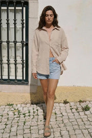 Camisa de fit oversized, cuello camisero, manga larga con puño abotonado, pinza de amplitud en espalda, bolsillo frontal, bajo curveado y cierre frontal con hilera de botones.