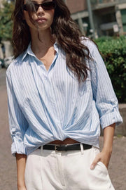 Camisa corta de estampado rayas, fit recto, manga larga rolled up con trabilla ajustable, cuello camisero, cruce frontal con escote v y nudo decorativo en bajo. Detalle de bajo curveado y pinza de amplitud en espalda.