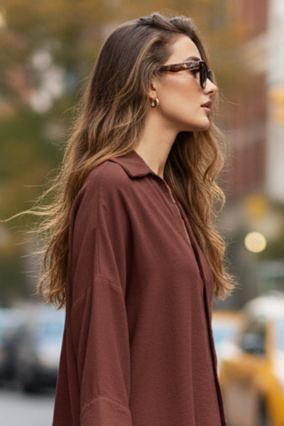 Camisa de fit oversized, manga 3/4 amplia con doblez en puños, cuello camisero, escote v, pinza de amplitud en espalda con trabilla decorativa y bajo curveado. Cierre frontal con hilera de botones en contraste.